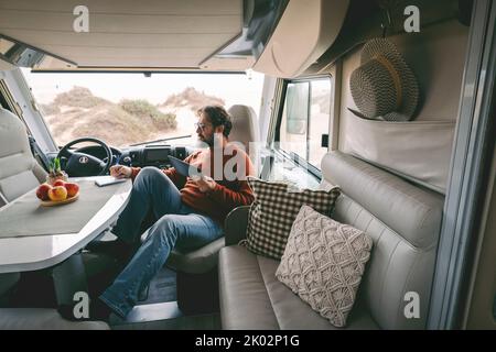 Vue intérieure de la femme voyageur appréciant le coucher du soleil sur la porte du camping-car. Voyage et style de vie de Wanderlust concept moderne de gens branchés. Femme avec des chapeaux vie et liberté indépendantes Banque D'Images