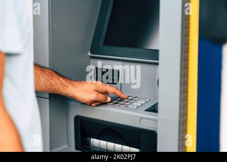 Gros plan de l'homme main retirer de l'argent à la machine automatique atm en tapant le code secret de sécurité numéro. Concept de l'activité bancaire et du travail d'entreprise. Guichet automatique extérieur pour les personnes et la banque Banque D'Images