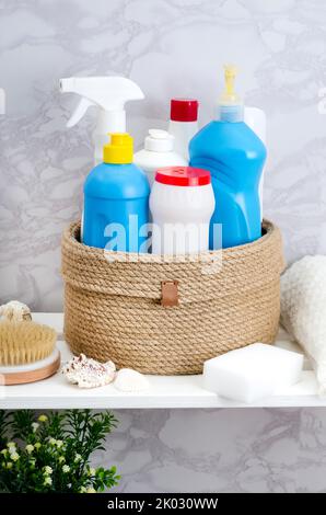 Panier en jute tricoté à la main avec un couvercle avec des détergents et des serviettes dans la salle de bains sur un rack en bois blanc Banque D'Images