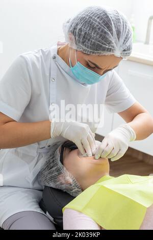 Dentiste installant un rétracteur de joue de patient dans un cabinet de dentiste Banque D'Images