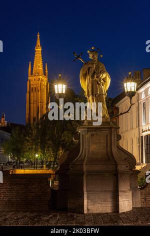 Statue de Saint-Jean-Nepomuk et tour de l'église notre-Dame la nuit. Bruges, Flandre, Belgique. Banque D'Images