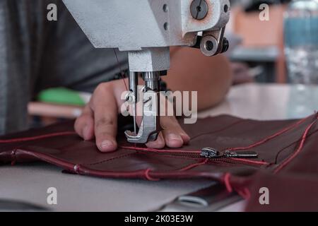 Les coutures de couturière à la machine à coudre filent le tissu. Mains des femmes Banque D'Images