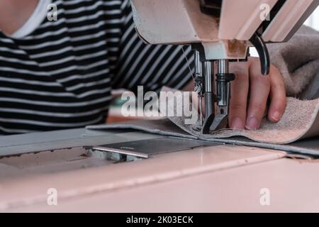 Les coutures de couturière à la machine à coudre filent le tissu. Mains des femmes Banque D'Images