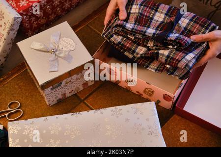 Gros plan sur les mains d'une femme qui enveloppent les cadeaux de Noël Banque D'Images