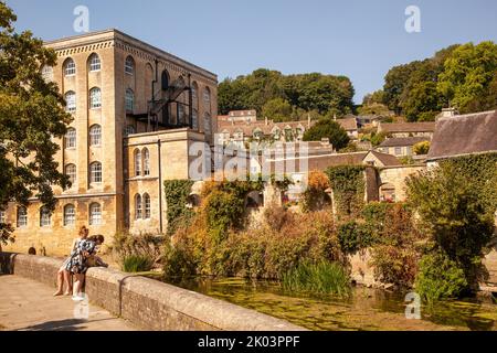 Les gens sur la promenade le long des rives de la rivière Avon à Bradford sur Avon Wiltshire avec une vue sur l'ancien moulin de l'abbaye Banque D'Images