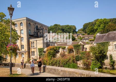 Les gens sur la promenade le long des rives de la rivière Avon à Bradford sur Avon Wiltshire avec une vue sur l'ancien moulin de l'abbaye Banque D'Images