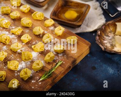 Cuisson de boulettes maison classiques, raviolis. Petits boulettes, raviolis sur une planche à découper en bois avec une branche de romarin parfumé. Ingrédients, cuisine Banque D'Images