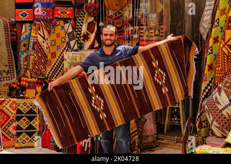 Orienter Street shop de souvenirs traditionnels textiles produits à la main dans le bazar dans la région de la vieille ville. Vendeur de tapis proposant des tapis orientaux du Moyen-Orient. Banque D'Images