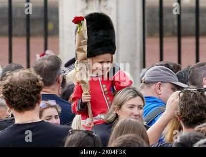 © Jeff Moore Une jeune fille habillée comme garde s'assoit sur les épaules de sa mère alors qu'elle paie son respect pour la Reine Elizabeth II à l'extérieur de Buckingham P. Banque D'Images