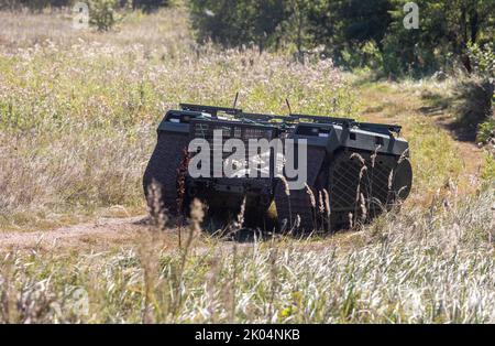 Un drone à chenilles multifonction THEMIS est vu sur une route poussiéreuse lorsqu'il porte un combattant blessé lors des essais sur le terrain. Essais sur le terrain du drone à chenilles multifonction THEMIS de la société estonienne Milrem Robotics qui sera utilisé pour l'évacuation sur le front des soldats blessés par le bataillon médical 'Hospitalers'. Le robot d'évacuation Zhuravel a réussi le premier test. Le robot sera utilisé sur la ligne de front, dans les endroits où il est difficile pour les médecins d'atteindre par véhicule ou à pied. Banque D'Images