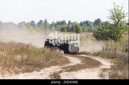 Un drone à chenilles multifonction THEMIS est vu sur une route poussiéreuse lorsqu'il porte un combattant blessé lors des essais sur le terrain. Essais sur le terrain du drone à chenilles multifonction THEMIS de la société estonienne Milrem Robotics qui sera utilisé pour l'évacuation sur le front des soldats blessés par le bataillon médical 'Hospitalers'. Le robot d'évacuation Zhuravel a réussi le premier test. Le robot sera utilisé sur la ligne de front, dans les endroits où il est difficile pour les médecins d'atteindre par véhicule ou à pied. Banque D'Images