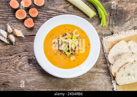 Patate douce végétalienne, soupe à la crème de poireaux avec morceaux de tofu frits. Servi sur une table en bois rustique. Vue de dessus. Légumes frais comme décoration. Sans gluten. Banque D'Images