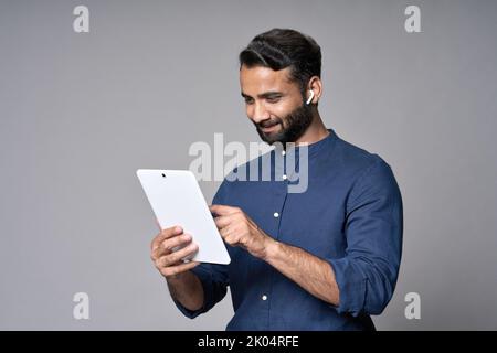 Homme d'affaires indien heureux utilisant une tablette isolée sur fond gris. Banque D'Images