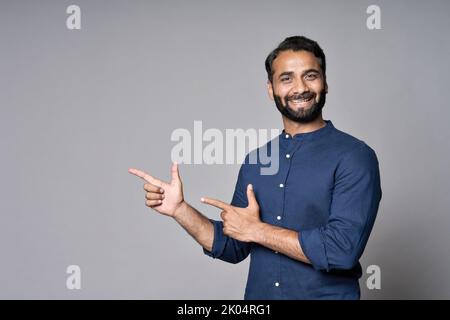 Un homme d'affaires indien heureux pointant des doigts de la publicité isolée sur gris. Banque D'Images