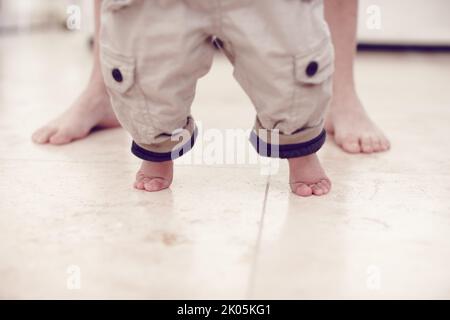 Prendre ces premiers pas provisoires... vue courte d'un bébé garçon apprenant à marcher. Banque D'Images