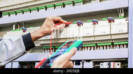 Testeur de travail électricien mesurant la tension et le courant de la ligne électrique d'alimentation dans le contrôle d'armoire électrique. Banque D'Images