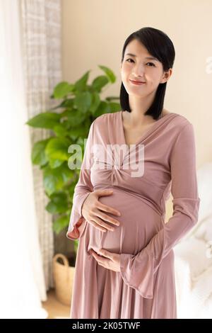 Chinois joyeuse femme enceinte détente à la maison Banque D'Images