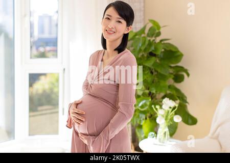 Chinois joyeuse femme enceinte détente à la maison Banque D'Images