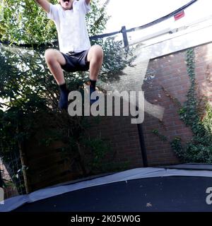 Un garçon méconnaissable sautant sur un trampoline. Il est plein de joie Banque D'Images