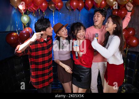 De jeunes amis chinois qui chantent du karaoké à la discothèque Banque D'Images