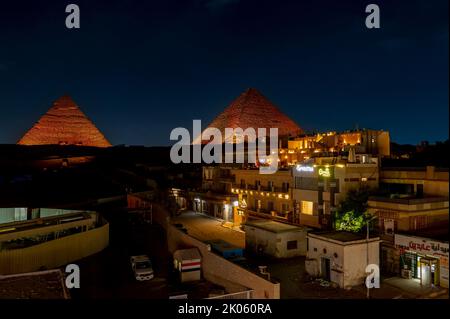 Le Caire/Égypte. 08/28/2022.vue sur une rue au Caire et les Pyramides illuminées de Cheops et Khafre en arrière-plan Banque D'Images