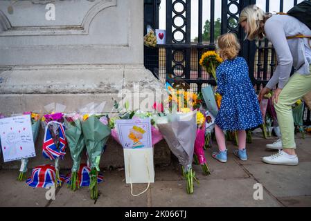 Westminster, Londres, Royaume-Uni. 10th septembre 2022. Après la mort de la Reine jeudi, les membres du public se sont réunis au Palais de Buckingham pour honorer son décès et laisser des fleurs, des cadeaux et des messages. Jeune fille plaçant des fleurs Banque D'Images