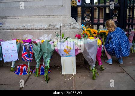 Westminster, Londres, Royaume-Uni. 10th septembre 2022. Après la mort de la Reine jeudi, les membres du public se sont réunis au Palais de Buckingham pour honorer son décès et laisser des fleurs, des cadeaux et des messages. Jeune fille plaçant des fleurs Banque D'Images