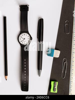 Stylo, crayon, gomme, taille-crayon, montre-bracelet et règle sur fond noir et blanc contrasté Banque D'Images
