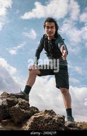 Coureur de sentier mâle chinois debout sur le rocher Banque D'Images