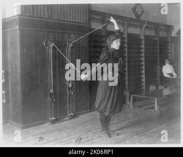 Une étudiante s'exerçant avec un appareil mural utilisant des cordes et des poulies, Western High School, Washington, D.C., (1899?). Banque D'Images