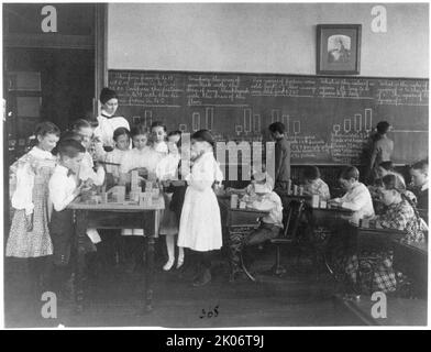 Scène en classe à Washington, D.C., école primaire - enfants travaillant avec des blocs et au tableau noir en classe de mathématiques, (1899?). Banque D'Images