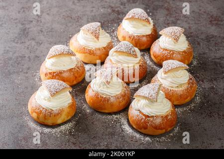 Petits pains sucrés Semla ou semlor avec cardamome, remplis de pâte d'amande et de crème fouettée sur la table. Horizontale Banque D'Images