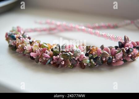 Bijoux en perles, collier de décoration fait main fait de perles et de pierres de différentes couleurs sur une table blanche Banque D'Images