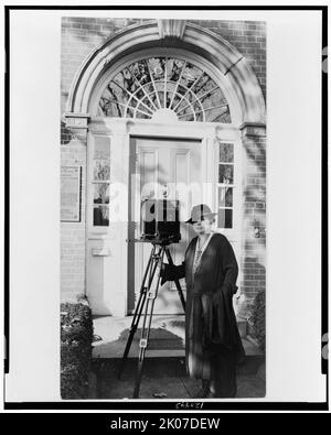 Frances Benjamin Johnston, portrait intégral, debout devant la porte, avec appareil photo, légèrement à gauche, c1935. Banque D'Images