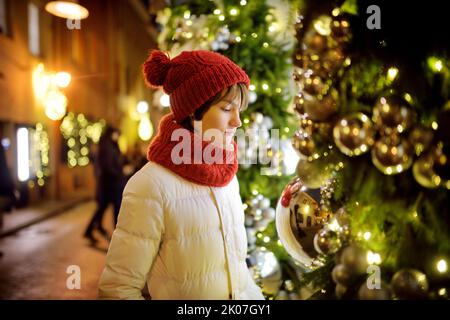 Jolie jeune fille admirant les lumières et les décorations de Noël dans les rues de Vilnius, Lituanie. Enfant admirant les arbres de Noël décorés la nuit. Gagnez Banque D'Images