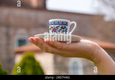 Une tasse de café turc sur la paume, sur fond d'architecture turque traditionnelle Banque D'Images