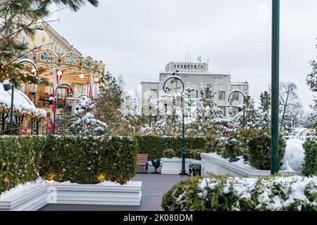 Carrousel festif à la place d'hiver parmi les trees de noël. Paysage urbain magique et enneigé. Banque D'Images