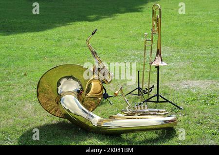 Divers instruments de musique en laiton comme le Sousaphone, le trombone et le saxophone placés sur la pelouse dans le parc et attendant d'être utilisés dans le groupe de musique, cop Banque D'Images