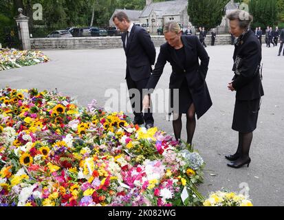 (De gauche à droite) les petits-enfants de la reine Elizabeth II, Peter Phillips et Zara Tindall, ainsi que sa fille, la princesse royale, voient des fleurs laissées par des membres du public à Balmoral, en Écosse, après le décès de la reine Elizabeth II, jeudi. Date de la photo: Samedi 10 septembre 2022. Banque D'Images