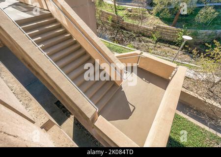 Vue depuis le dessus des escaliers extérieurs allant à l'intérieur d'un bâtiment à Austin, Texas. Regarder vers le bas sur un escalier avec des marches en béton et des rampes en métal sur un soleil Banque D'Images