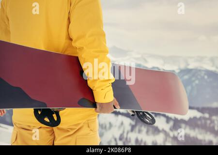 Photo en gros plan d'un vrai snowboardeur debout avec le snowboard entre les mains. Concept de station de ski Banque D'Images