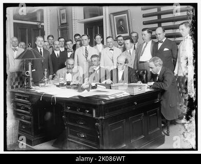 Groupe : comprend William Jennings Bryan (au bureau, 2nd à partir de la droite); et Josephus Daniels, au milieu de 2nd rangs, entre 1910 et 1920. Les politiciens américains. Bryan était avocat et secrétaire d'État. Daniels était rédacteur en chef et éditeur de journaux, et secrétaire de la Marine pendant la première Guerre mondiale. Notez la lampe électrique, la photographie encadrée et les téléphones à chandelier sur le bureau. Sur le mur derrière se trouve un portrait d'Abraham Lincoln. Banque D'Images