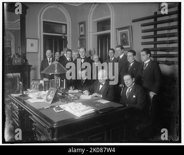 William Jennings Bryan avec groupe à la réception, entre 1910 et 1920. Bryan était avocat et secrétaire d'État. Notez la lampe électrique, la photographie encadrée et les téléphones à chandeliers sur le bureau. Sur le mur derrière se trouve un portrait d'Abraham Lincoln. Banque D'Images