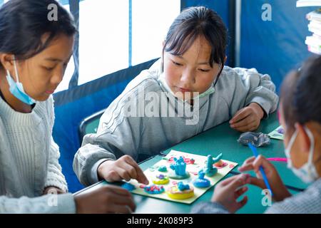 (220910) -- LUDING, le 10 septembre 2022 (Xinhua) -- les enfants de la ville de Detuo font des 'gâteauxs' créatifs avec de la plasticine dans une 'salle de classe de tente' au refuge de secours de séisme de l'école secondaire Luding no 2 à Luding, dans le sud-ouest de la Chine, province du Sichuan, le 10 septembre 2022. Après un tremblement de terre de magnitude 6,8 qui a secoué le comté de Luding dans la province du Sichuan, dans le sud-ouest de la Chine, lundi, plus de 800 villageois de la ville de Detuo, dont environ 50 enfants, ont été temporairement relogés dans le lycée de Luding no 2. Depuis 6 septembre, 11 enseignants des jardins d'enfants de Luding et 10 étudiants des collèges et du secondaire se sont portés volontaires Banque D'Images