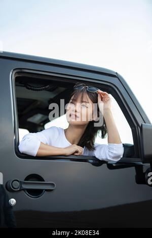 Bonne jeune femme chinoise regardant par la fenêtre de voiture Banque D'Images