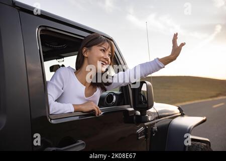 Bonne jeune femme chinoise regardant par la fenêtre de voiture Banque D'Images