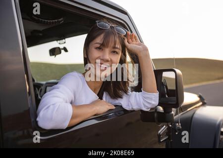 Bonne jeune femme chinoise regardant par la fenêtre de voiture Banque D'Images