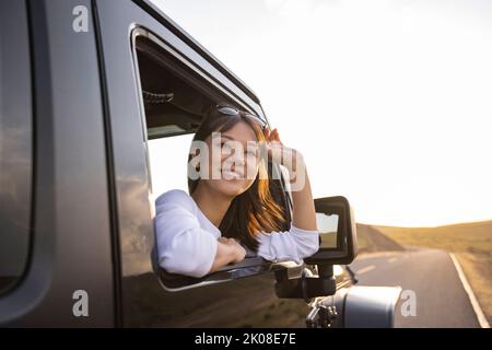 Bonne jeune femme chinoise regardant par la fenêtre de voiture Banque D'Images