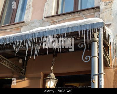 Des glaçons très pointus et de la neige fondue pendent des avant--toits de toit et de descente. Journée ensoleillée et glacial. Banque D'Images