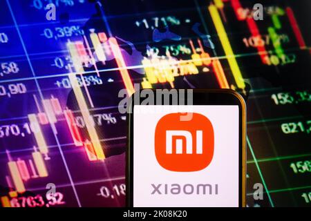 KONSKIE, POLOGNE - 10 septembre 2022: Smartphone affichant le logo de la société Xiaomi sur fond de diagramme boursier Banque D'Images